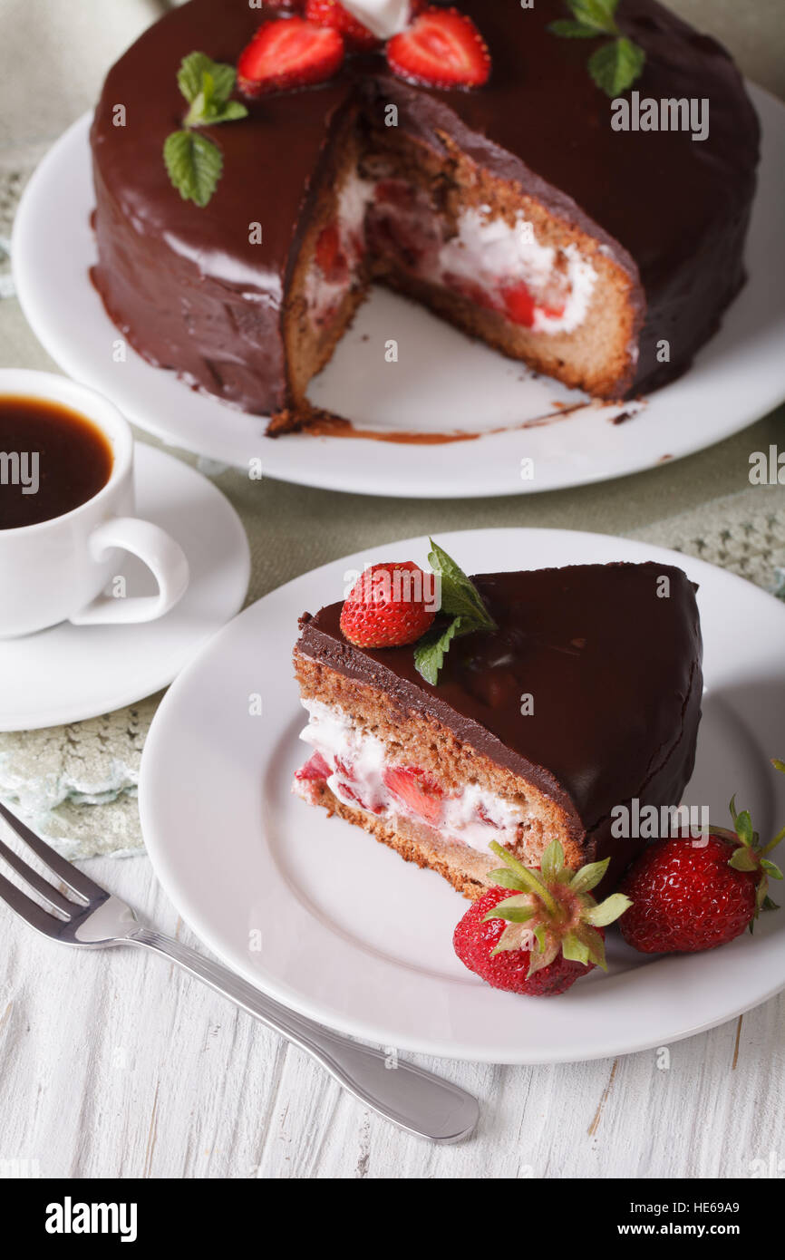 Tagliare la torta con fragole e cioccolato su una tavola di close-up. In verticale Foto Stock