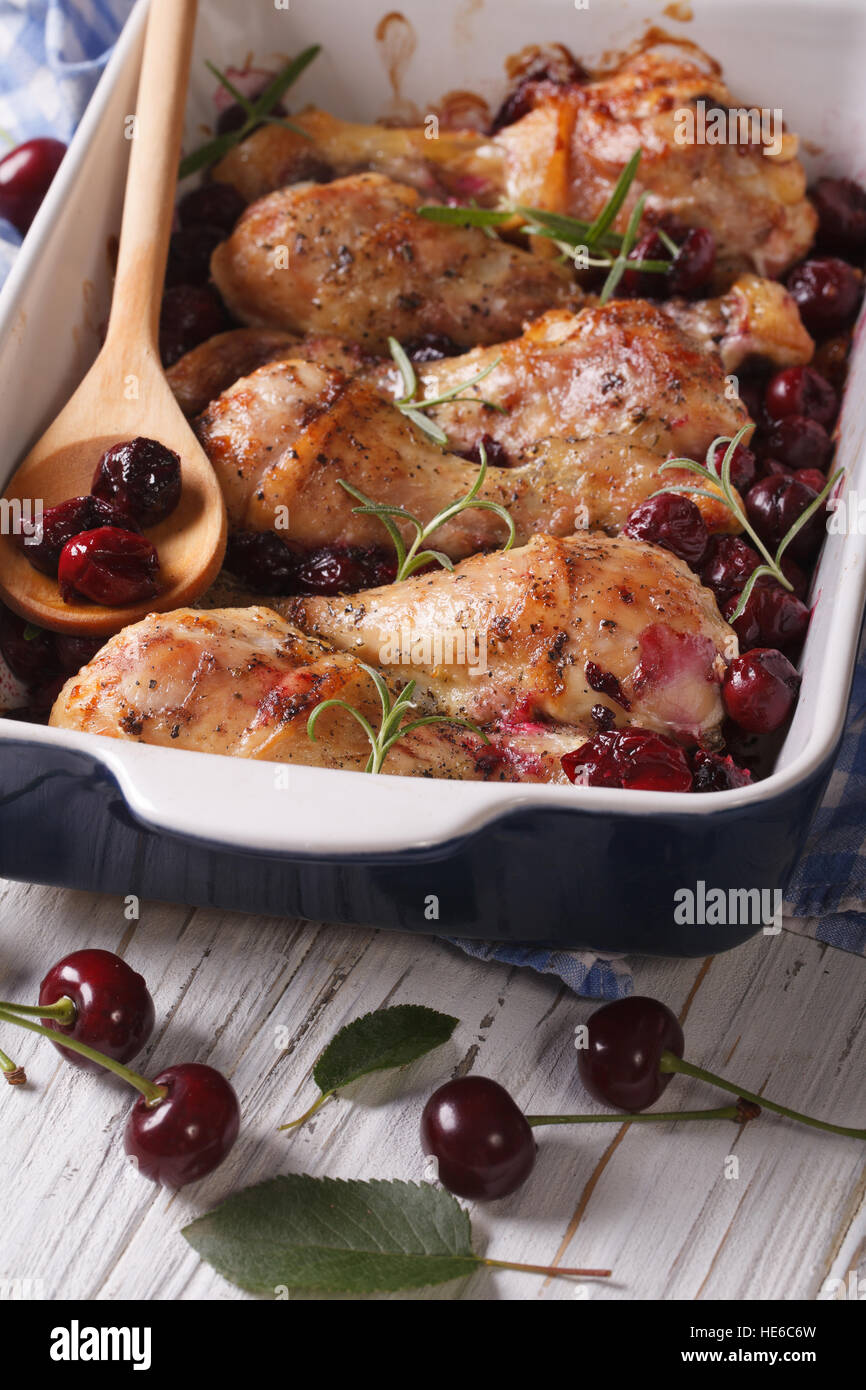 Il pollo al forno le gambe con la ciliegia matura e rosmarino close up verticale. Foto Stock