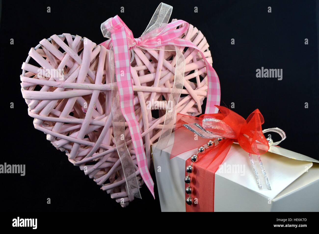 Scatola di praline e un cuore rosa con un nastro su uno sfondo nero Foto Stock