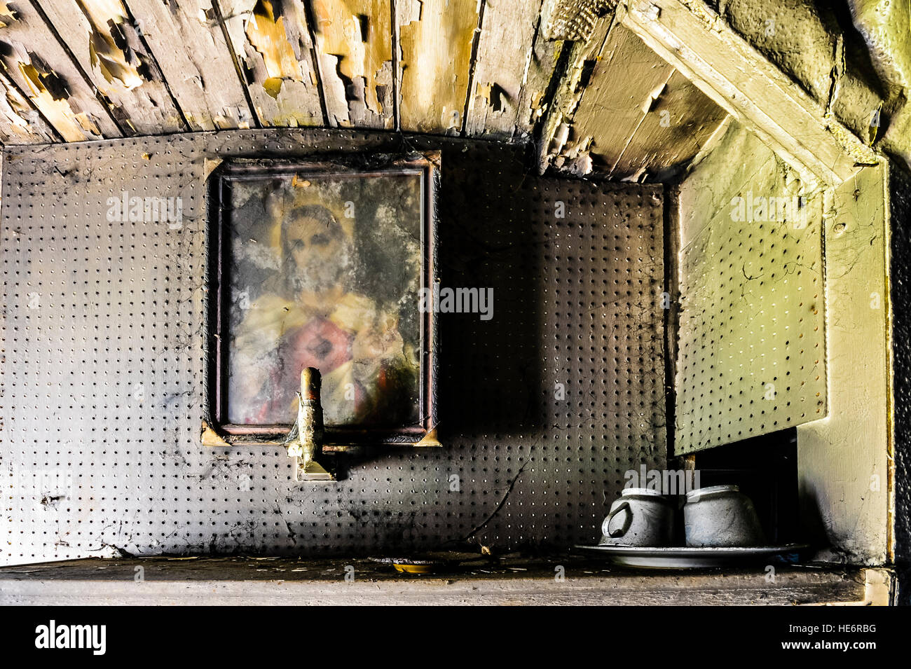 Un sacro cuore immagine di Gesù è appeso alla parete di un molto sporco house con peeling paint Foto Stock