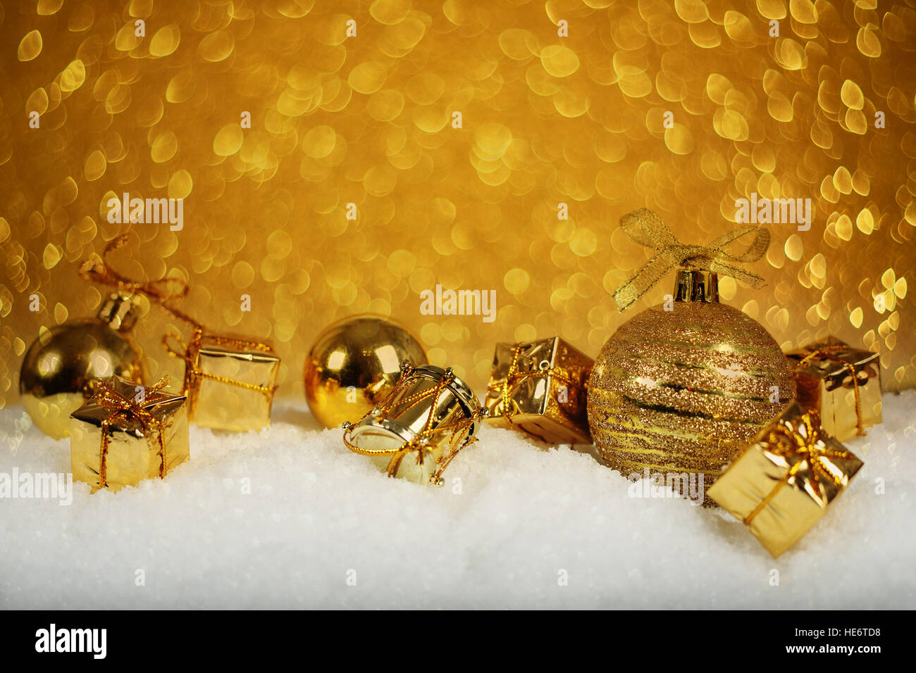 Golden decorazioni di Natale nella neve su sfondo glitter Foto Stock