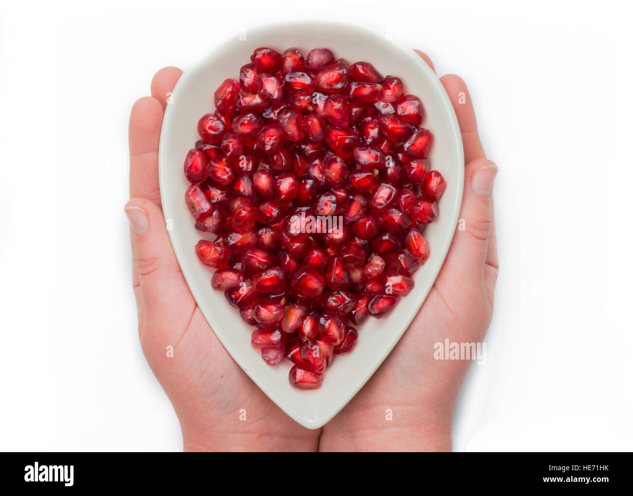 Le mani del bambino ragazzo o ragazza con frutta in una ciotola e colorati di rosso i semi di melograno, girato su sfondo bianco . isolato per copiare lo spazio . Foto Stock