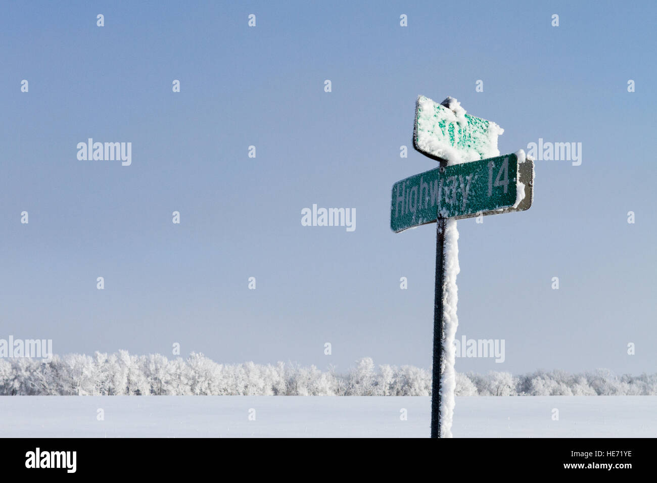Autostrada strada segno coperto di gelo e neve con il bianco della neve coperto i campi e gli alberi in background Foto Stock