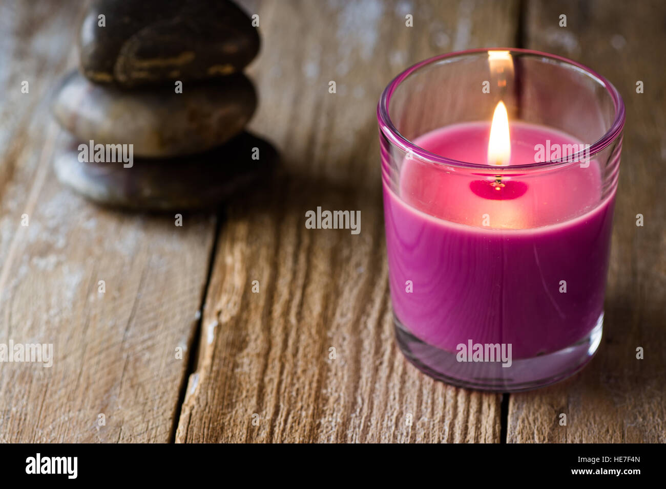 Lilla candela di lavanda e una pila di equilibrata pietre zen in background, sulla superficie di legno, copyspace per testo, il concetto di armonia Foto Stock