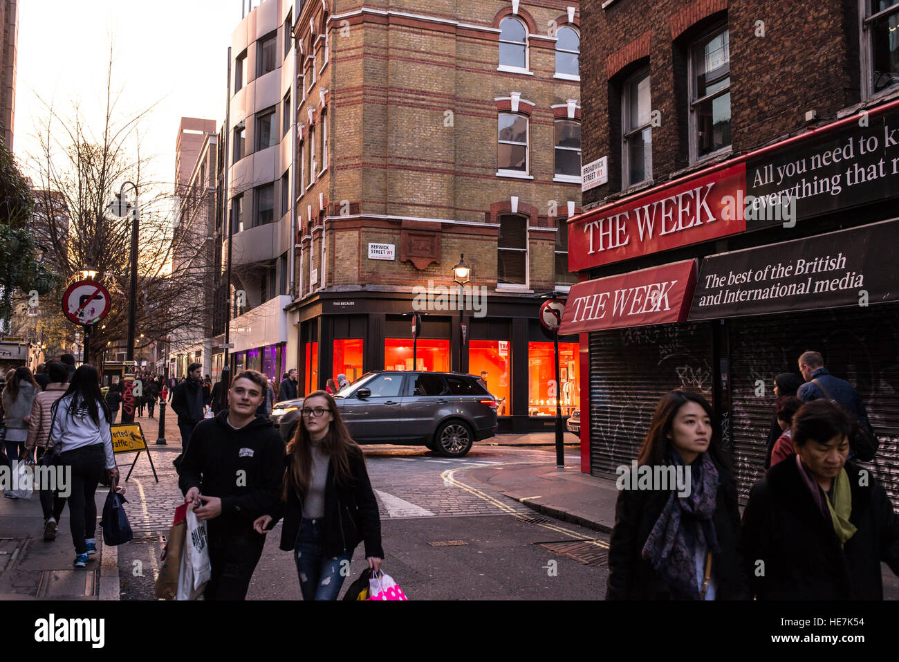 La gente a piedi in strada Broadwick, Soho, Londra nella parte anteriore della chiusura di un magazine shop con grande cartello sulla parte anteriore promuovendo la rivista britannica la settimana Foto Stock