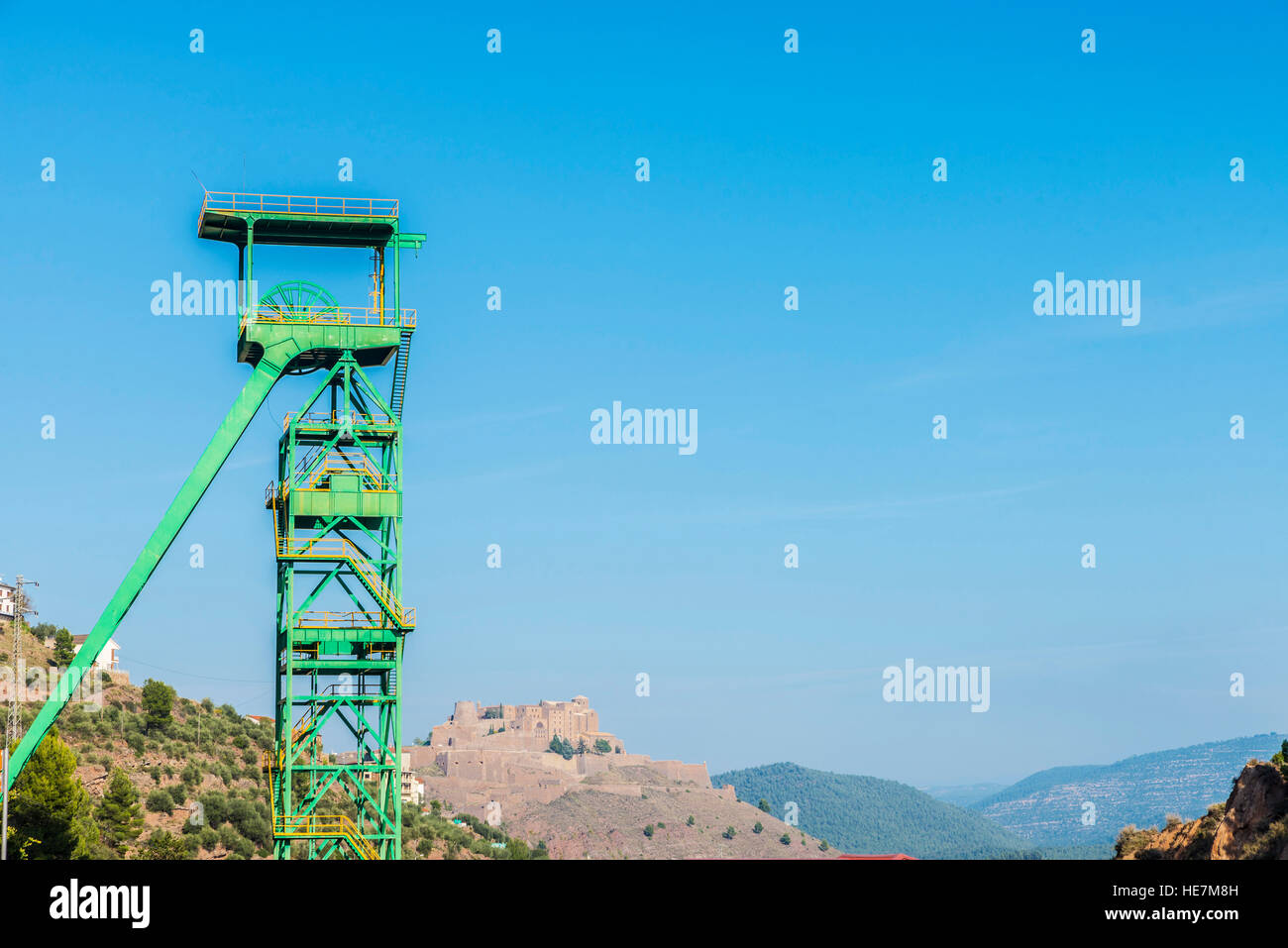 Torre verde di un pozzo di estrazione di una miniera di sale o di cloruro di potassio in disuso con il Castello di Cardona in background in Catalogna, Spagna Foto Stock