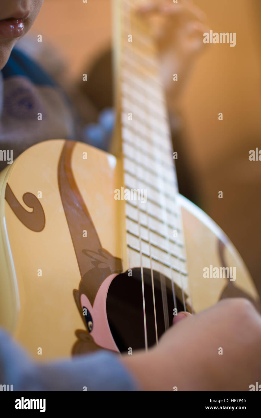 Ragazzo di suonare una chitarra decorata con una scimmia Foto Stock