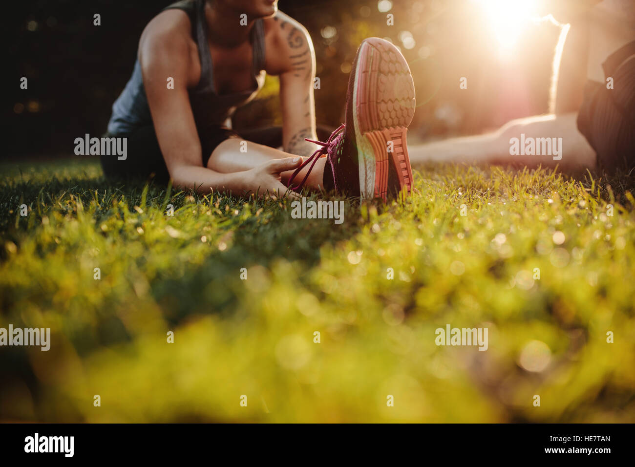Ritagliato colpo di montare la giovane donna stretching al parco con l'uomo. Focus su piedi di femmina. Foto Stock
