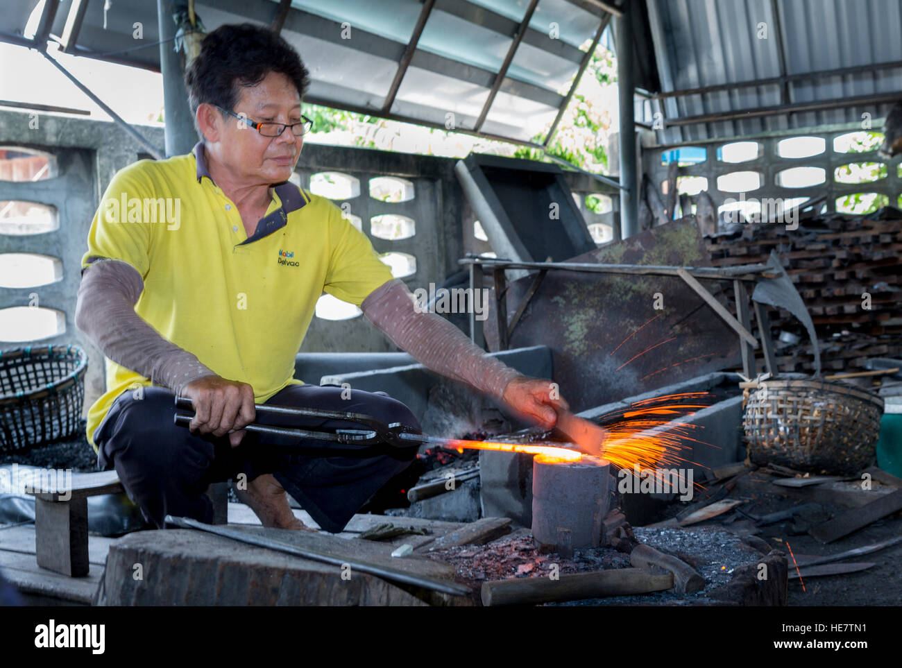 Ajam Kor Neekow e sua fabbri / bladesmiths facendo una spada tradizionali a loro forge in Lampang, Thailandia Foto Stock
