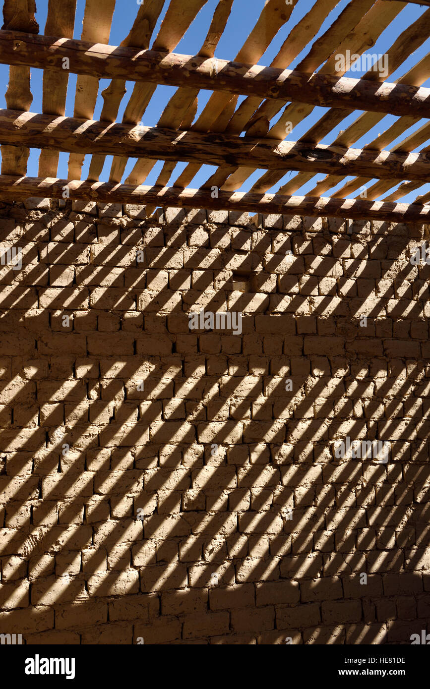 Strisce di ombra di soffitto in legno e travi di spranghe sul fango parete di mattoni a casa non finita vicino a shymkent Kazakistan Foto Stock