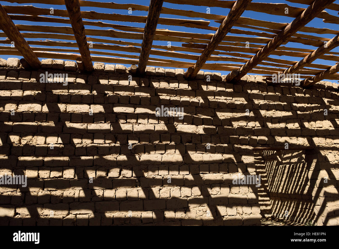 Modello di ombra di travi di legno e spranghe sul mattone di fango le pareti di casa non finita vicino a shymkent Kazakistan Foto Stock