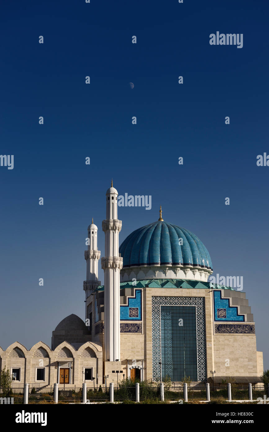 La luna nel cielo blu sopra i moderni hoca ahmet yesevi moschea nel Turkestan Kazakistan Foto Stock