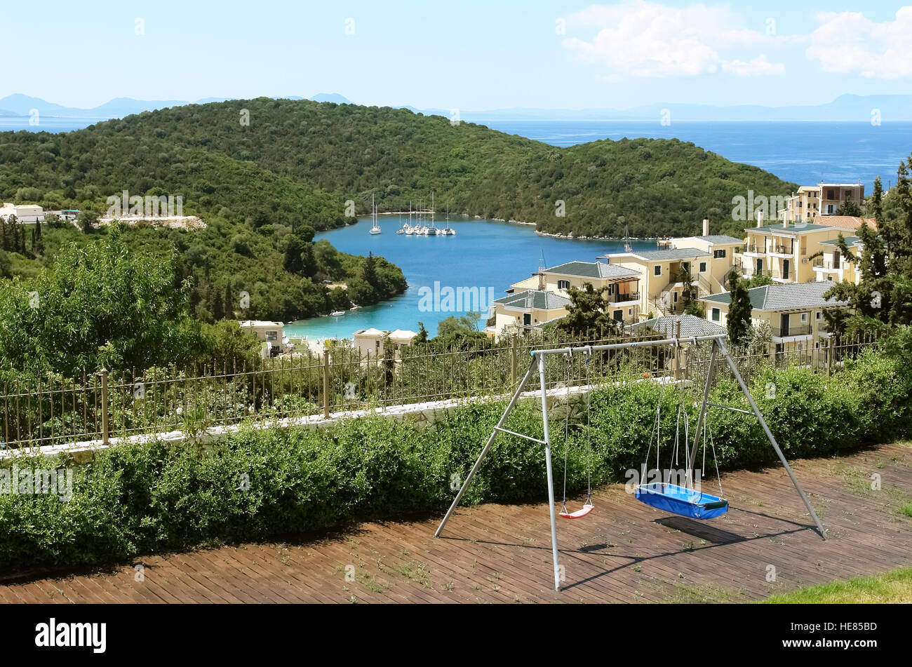 Swing e una vista della baia blu con montagne verdi e yacht nel Mar Ionio in Grecia. Foto Stock