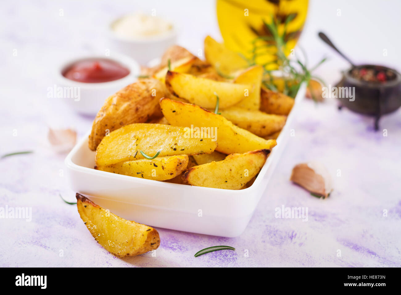 Ruddy patate al forno cunei con rosmarino e aglio su uno sfondo luminoso Foto Stock