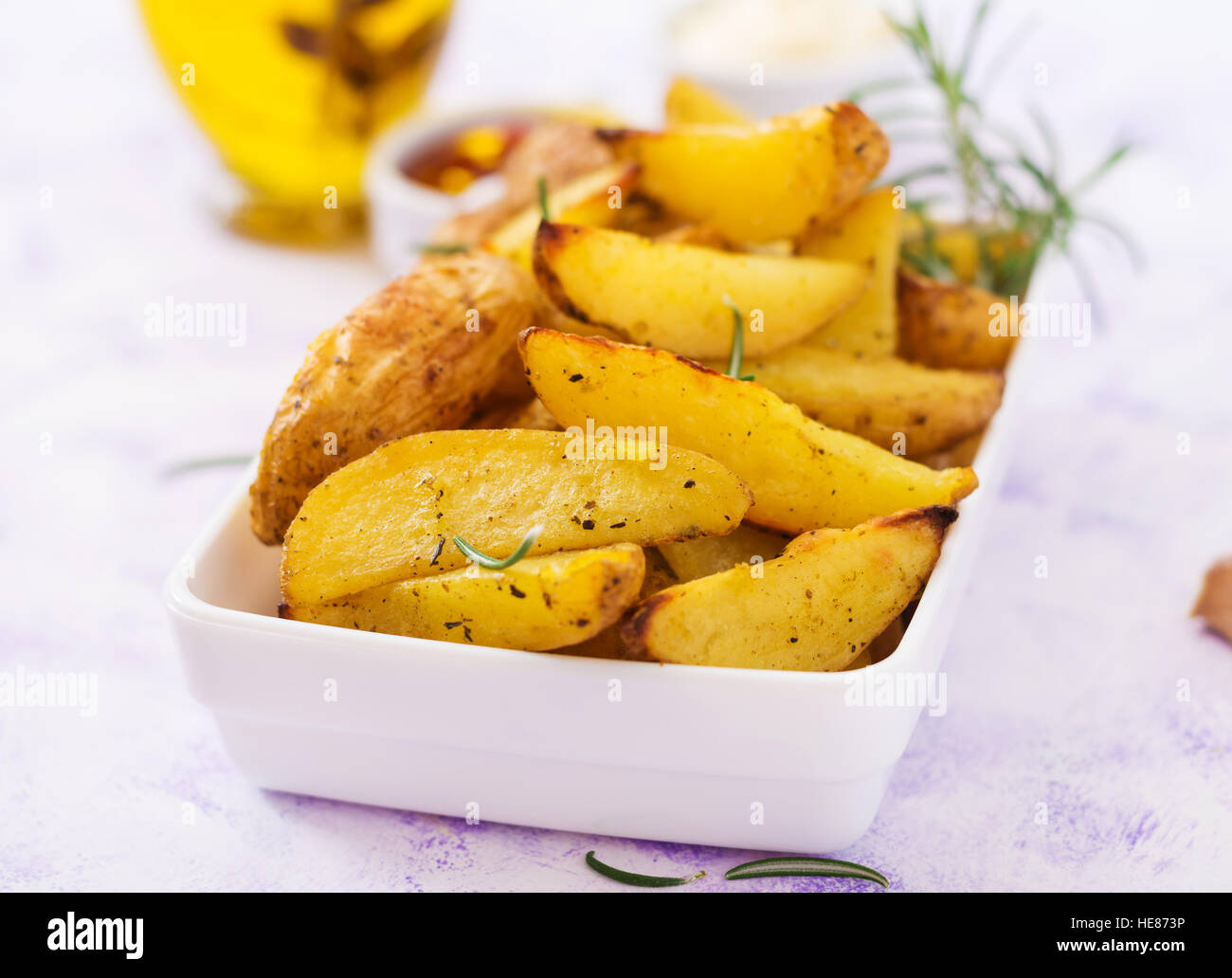 Ruddy patate al forno cunei con rosmarino e aglio su uno sfondo luminoso Foto Stock
