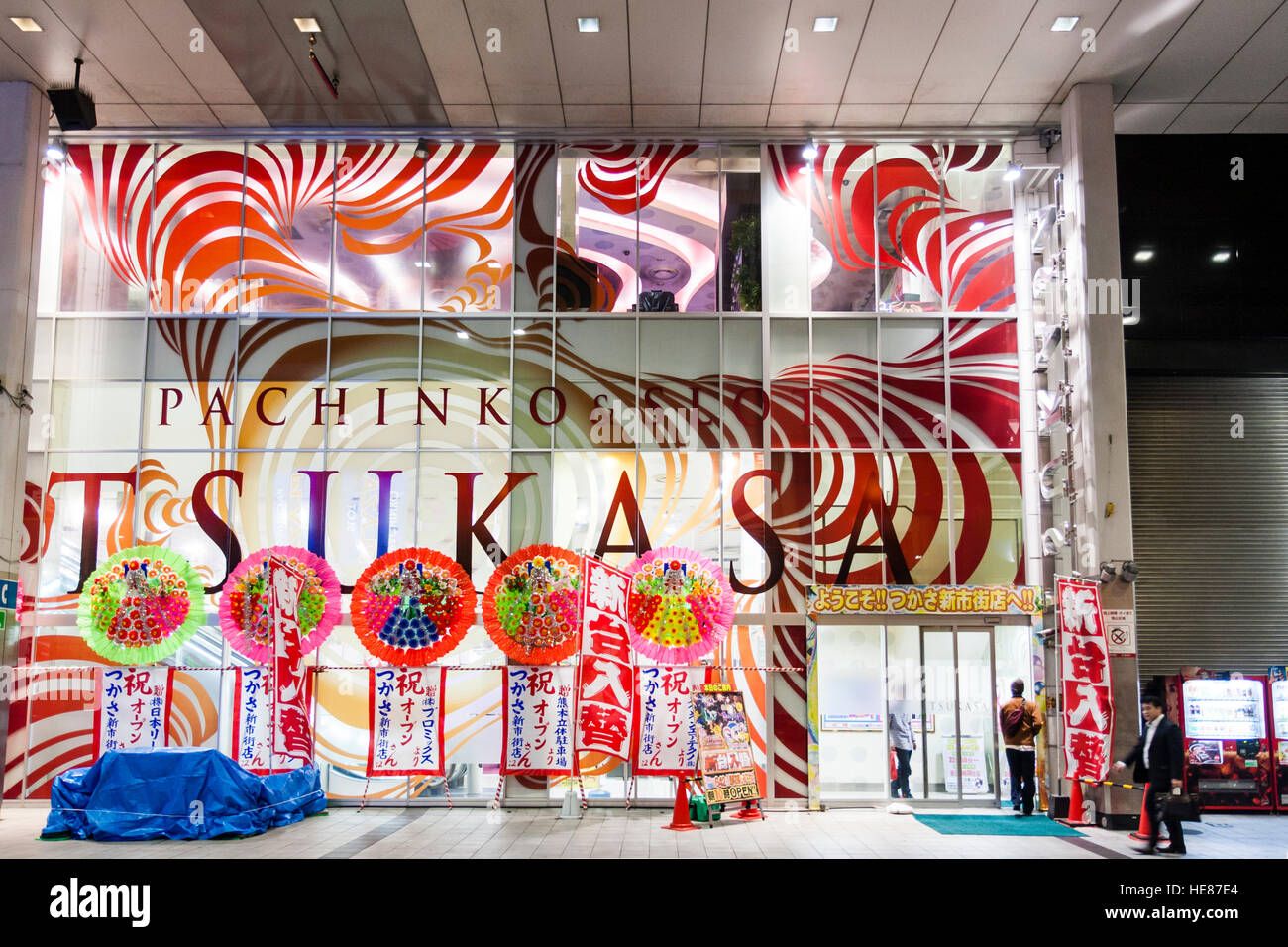 Giappone Kumamoto, Sun Road Shinshigai arcarde per lo shopping. "Tsukasai' ampio vetro frontale Pachinko e slot machine parlor. La notte. Persone. Foto Stock