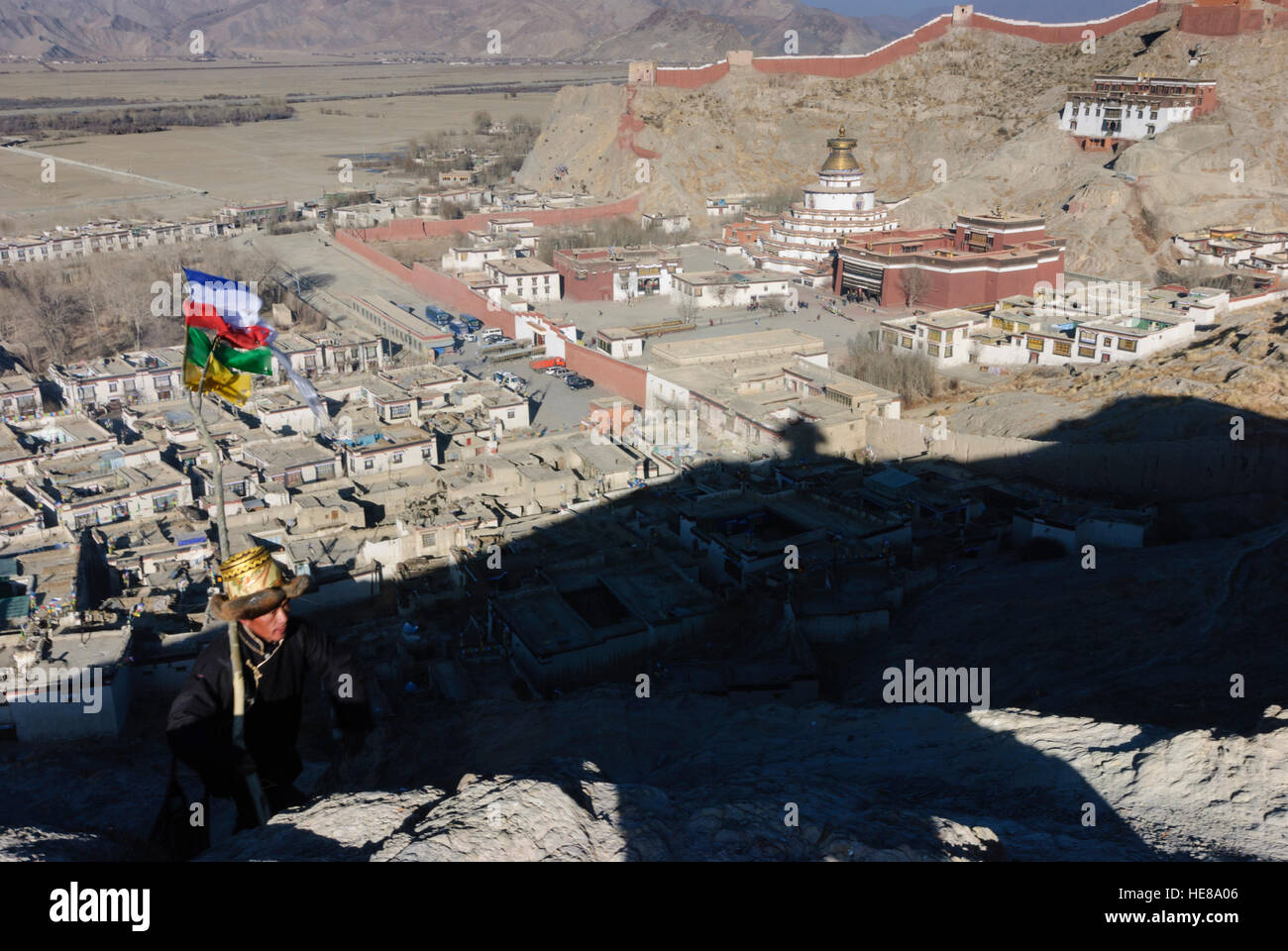 Gyantse: Città e Pelkor Chöde - monastero con Gyantse Kumbum e il monastero parete; tibetani salire la montagna con una preghiera bandiera attaccata alla f Foto Stock