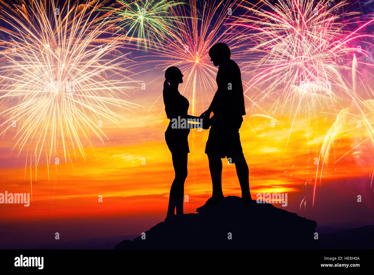 Coppia felice insieme sulla roccia e guardare i fuochi d'artificio colorati Foto Stock