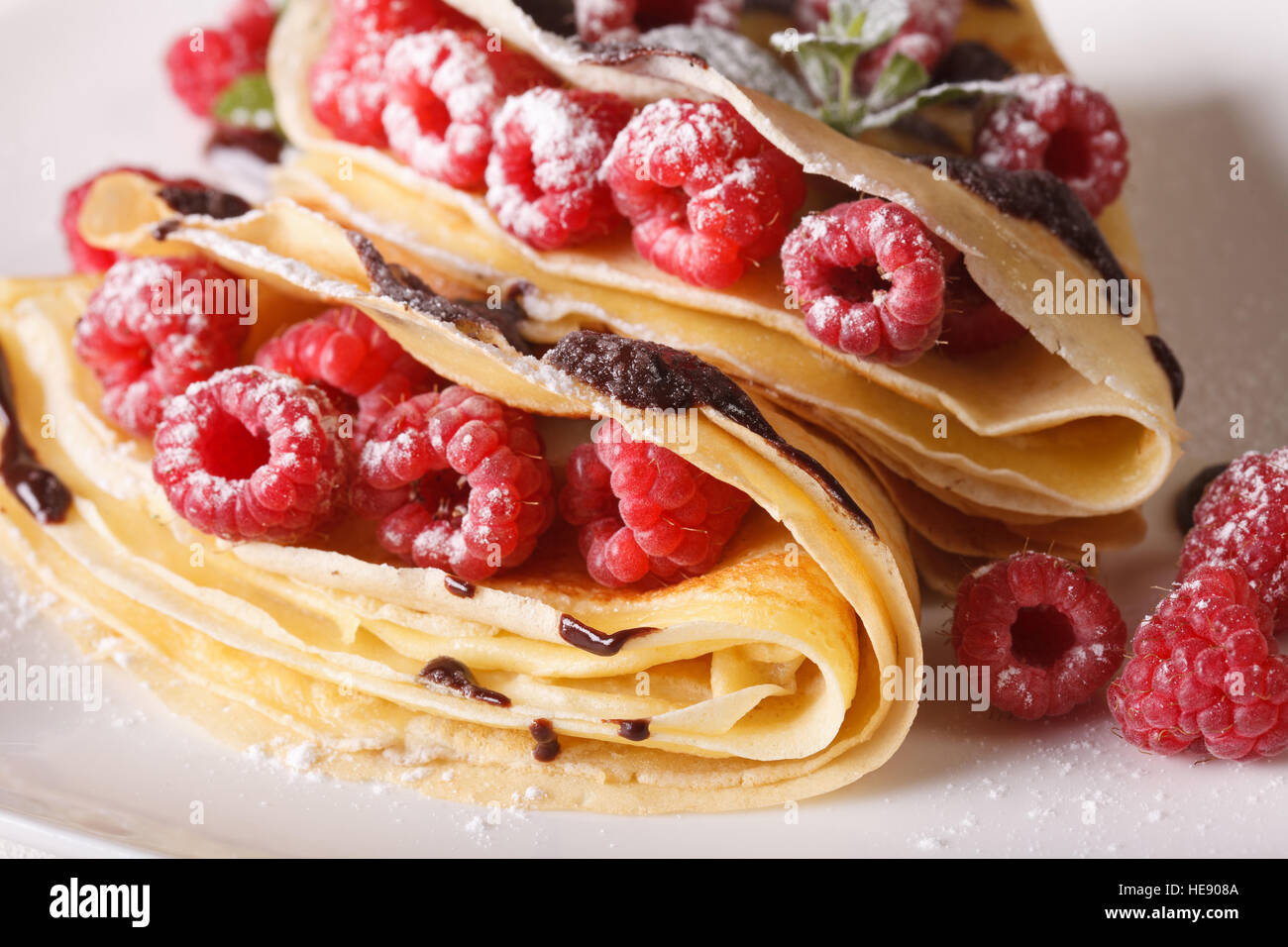 Bella lampone crepes con glassa di cioccolato macro su una piastra orizzontale. Foto Stock