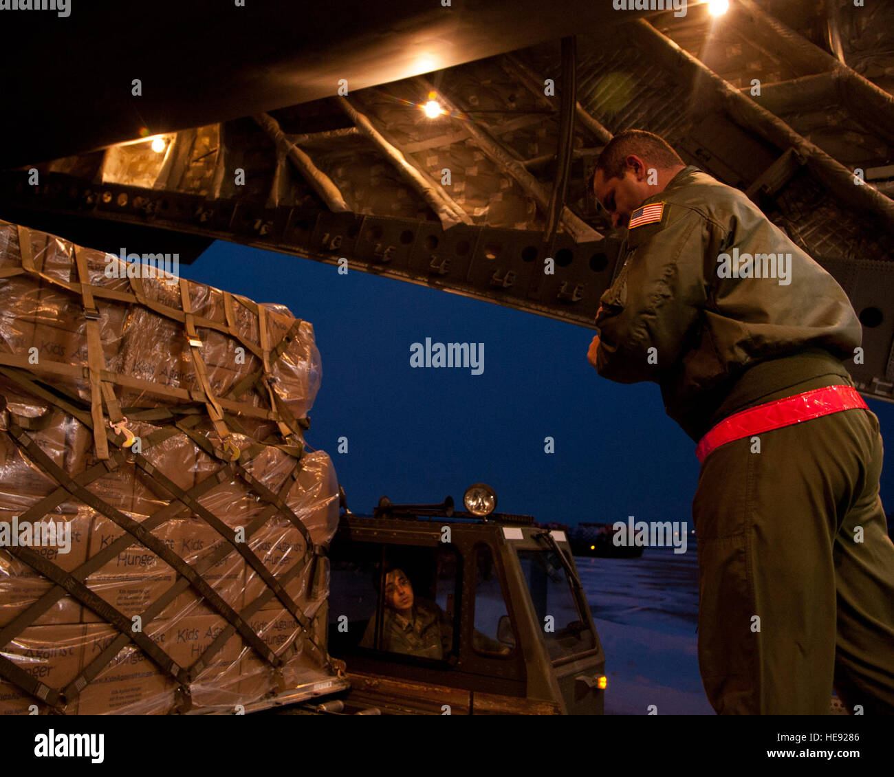 La ALTUS AIR FORCE BASE, Okla. -- Il personale Sgt. Brian Derosa, 58th Airlift Squadron loadmaster istruttore, dirige Airman 1. Classe Rimmer, 97th disponibilità logistica squadrone di trasporto aeree apprendista, durante il caricamento di una libbra di 137.000 aiuti umanitari spedizione, Dic 28, 2012. La spedizione è stata consegnata a Port-au-Prince, Haiti come parte del programma di Denton. È stato il più grande singolo giorno aiuti umanitari consegna dal 1998. Senior Airman Kenneth W. Norman / rilasciato) Foto Stock
