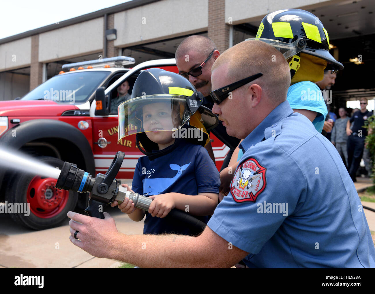 Un giovane partecipa al programma Pilot for a Day con il reparto vigili del fuoco del 97th Civil Engineer Squadron il 26 giugno 2015, impegnato in attività antincendio e scortato ad un briefing di missione con il 58th Airlift Squadron. Foto Stock