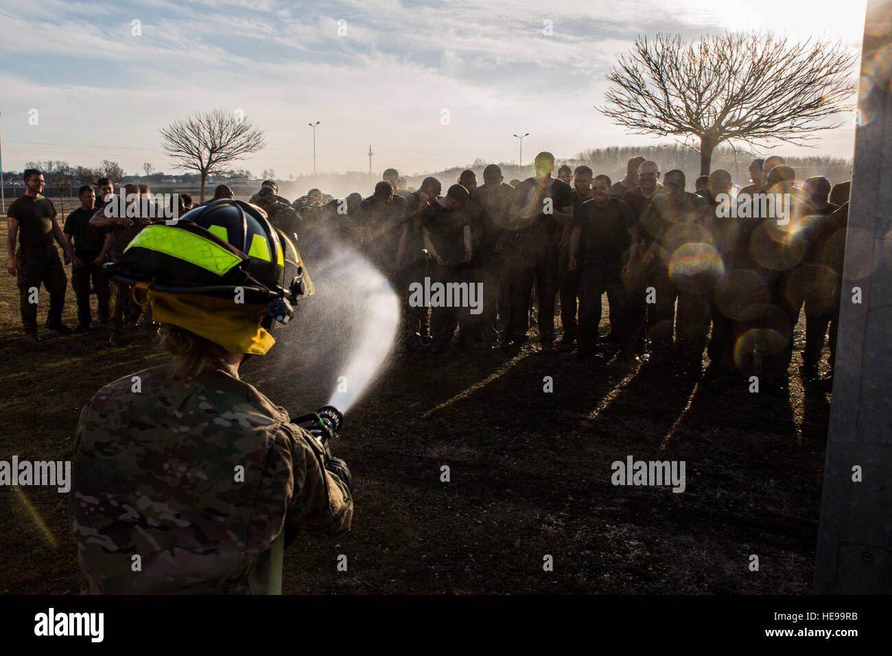 Stati Uniti Esercito vigili del fuoco con il Mihail Kognaliceanu Air Base dei Vigili del fuoco utilizza un tubo flessibile di acqua per il lavaggio di fango U.S. Marines con il Mar Nero La forza di rotazione dopo che partecipare a un torneo di stile esercizio alle prese a bordo Mihail Kognaliceanu Air Base, Romania, 29 gennaio, 2016. Marines con 1° Battaglione, 8° Reggimento Marine distribuito alla Romania per fornire U.S. Comando europeo la capacità di abilitare gli alleati della NATO e i paesi partner in Europa Orientale. Cpl. Tyler A. Andersen) Foto Stock