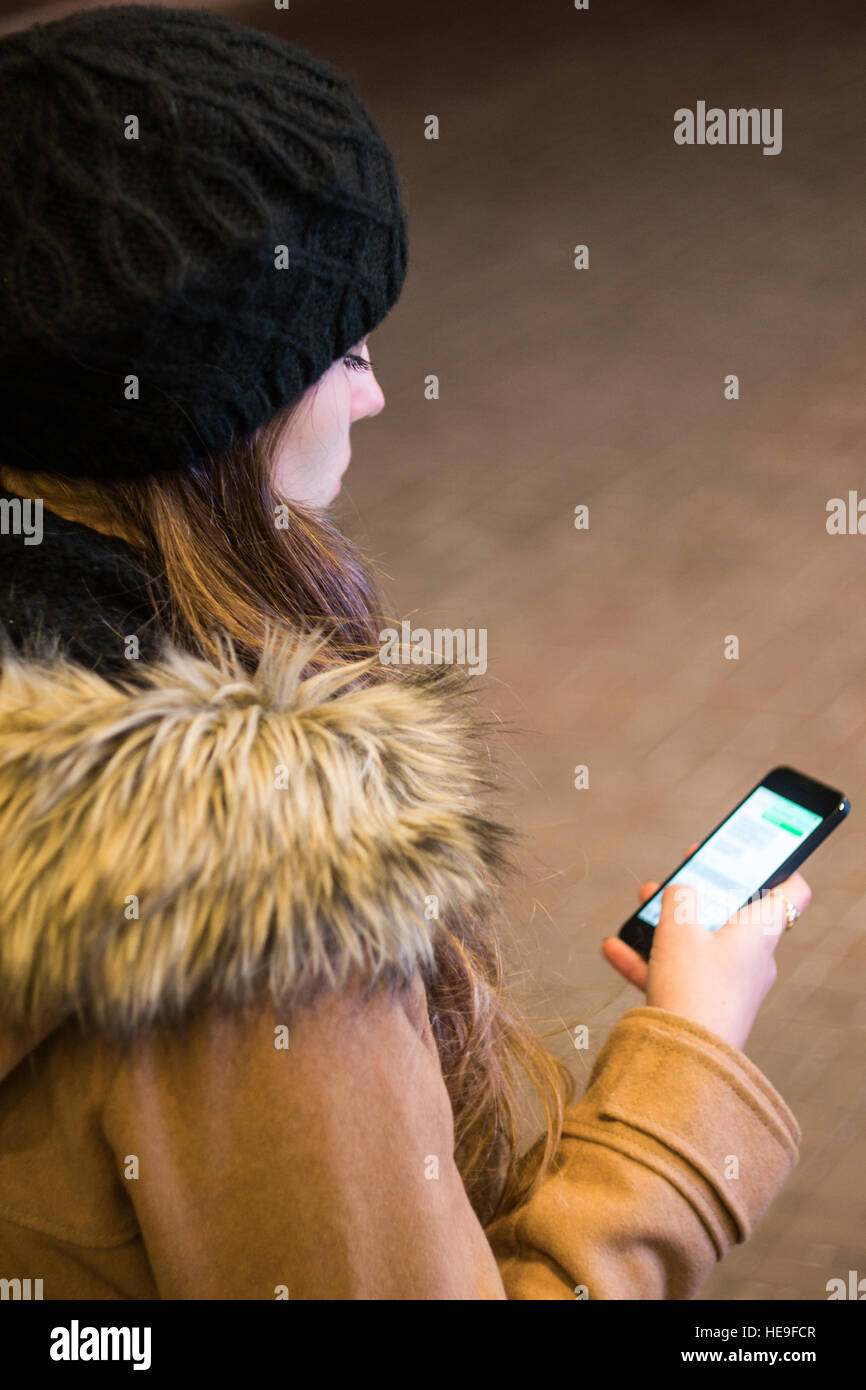 Donna texting su smart phone in una notte d'inverno Foto Stock
