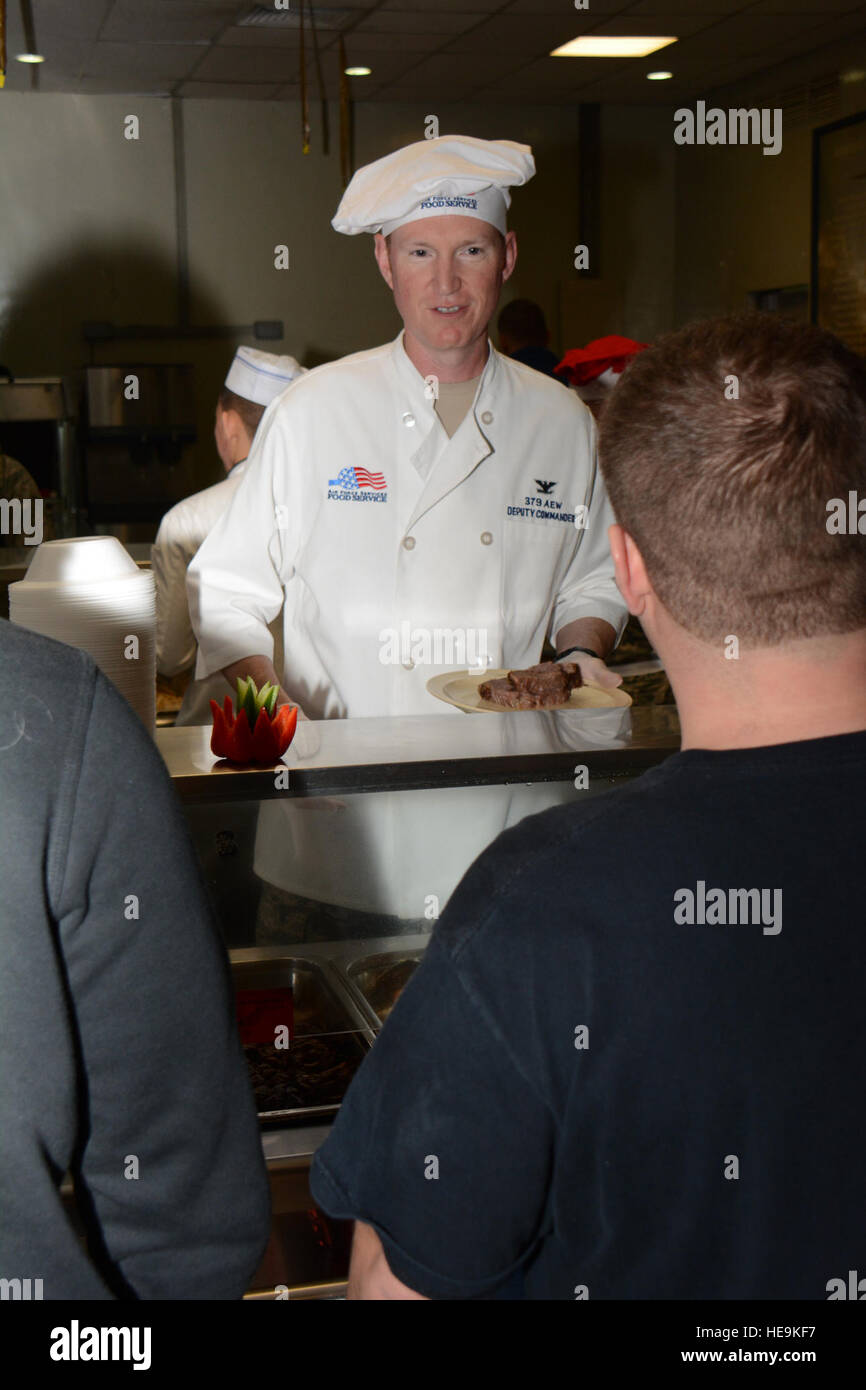 Col. Stuart Newberry, 379 Aria ala Expeditionary vice comandante, serve il pranzo per i membri del servizio all'Indipendenza struttura pranzo Al Udeid Air Base, Qatar, 25 dicembre. Newberry uniti parecchi membri della leadership AUAB nella tradizione della vacanza. Il menu vacanze featured aragosta, Turchia e una varietà di dessert compresi torte e gelati. Tech. Sgt. James Hodgman Foto Stock