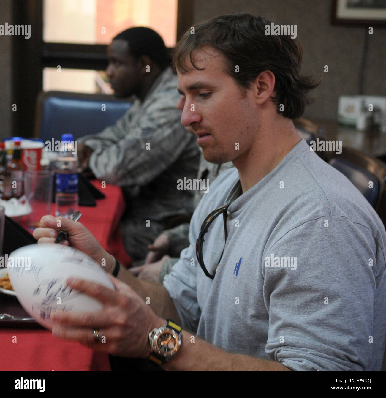 Drew Brees, quarterback dei New Orleans Saints e Super Bowl Most Valuable Player, autografi di un calcio per uno dei suoi tifosi durante il pranzo presso il Sultan's Inn dining facility Mercoledì, 24 marzo 2010 a Incirlik Air Base, Turchia. Brees, ex NFL linebacker Donnie Edwards e santi manualmente l'estremità Billy Miller ha visitato Incirlik come parte di un tour di OSU per incontrare e salutare negli Stati Uniti i membri del servizio. Senior Airman Ashley Wood Foto Stock