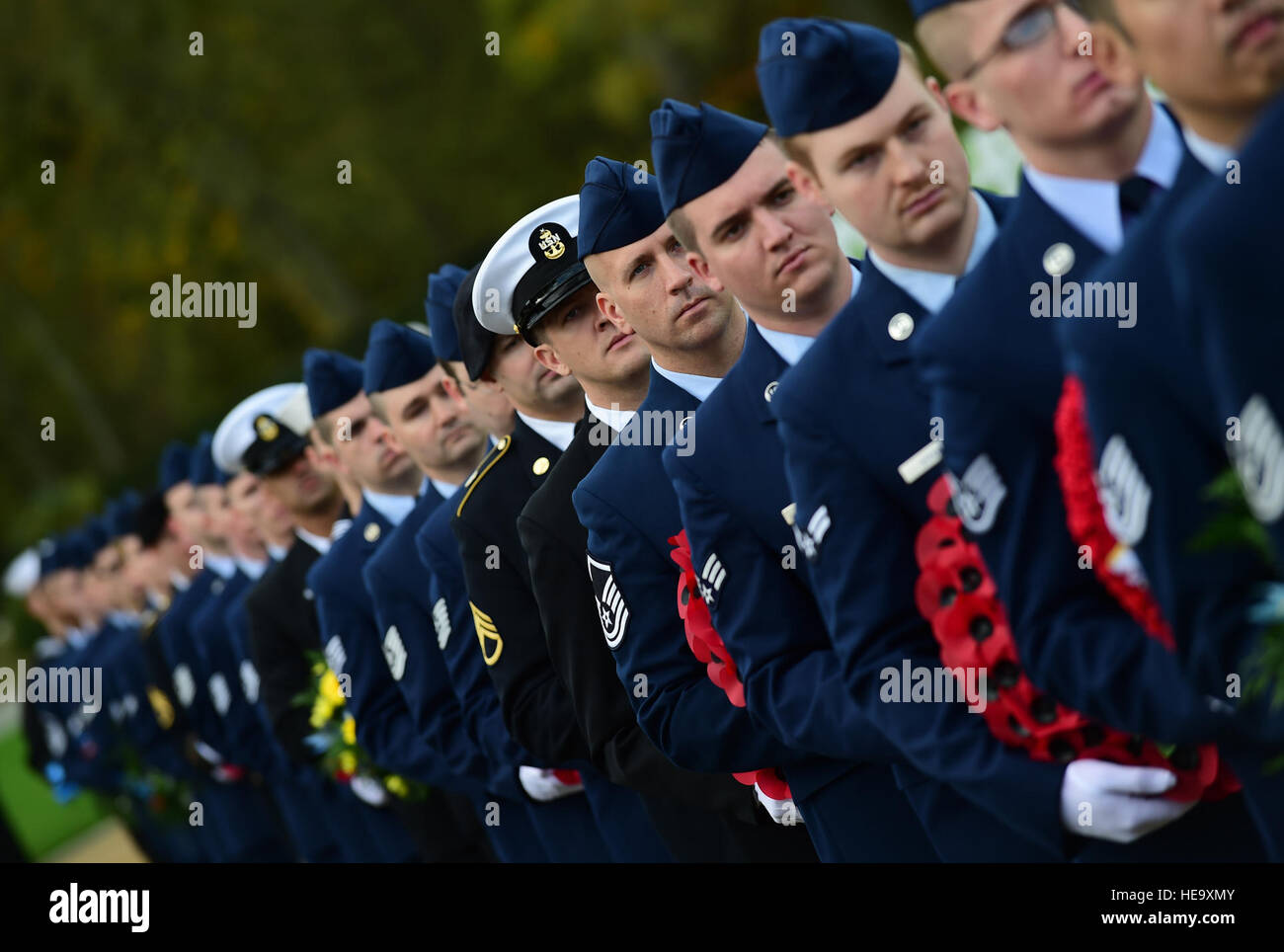 I membri del servizio del Dipartimento della Difesa, portano ghirlande durante il giorno dei veterani cerimonia al Cambridge Cimitero Americano, Regno Unito, nov. 11, 2015. Le corone sono state stabilite in onore i militari del passato e del presente. Master Sgt. Chrissy migliori Foto Stock