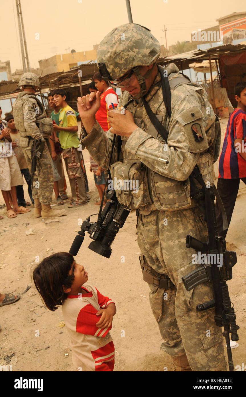 Stati Uniti Army Combat Cameraman Spc. Charles Probst della 55th Signal Company, FT Meade, Md., viene catturato off-guardia da un giovane iracheno bambino mentre egli cerca di mangiare qualche sherbert gelato mentre di pattuglia con U.S. Soldati del 432nd gli affari civili Battaglione e l'Ingegnere 926th brigata nell'Thawra 1 quartieri di Sadr City distretto di Baghdad in Iraq il 2 luglio 2008. I soldati sono operanti sotto Task Force Gold che è responsabile per la rivitalizzazione di corrente i progetti che sono in corso in Sadr City zona. Tech Sgt. Cohen A. Giovani Foto Stock