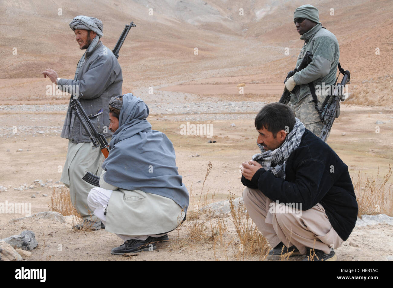 Sgt Casiano Benicio, le forze di sicurezza degli stati, Assegnati al Team di Ricostruzione Provinciale Ghazni, tira la sicurezza con i membri della polizia nazionale afgana mentre visitano il quartiere Nawur, provincia di Ghazni, Afghanistan. I membri del PRT ha visitato il quartiere Nawur per eseguire la garanzia di qualità Controllo di qualità su un karza collassato e due esaurienti cliniche. Foto Stock