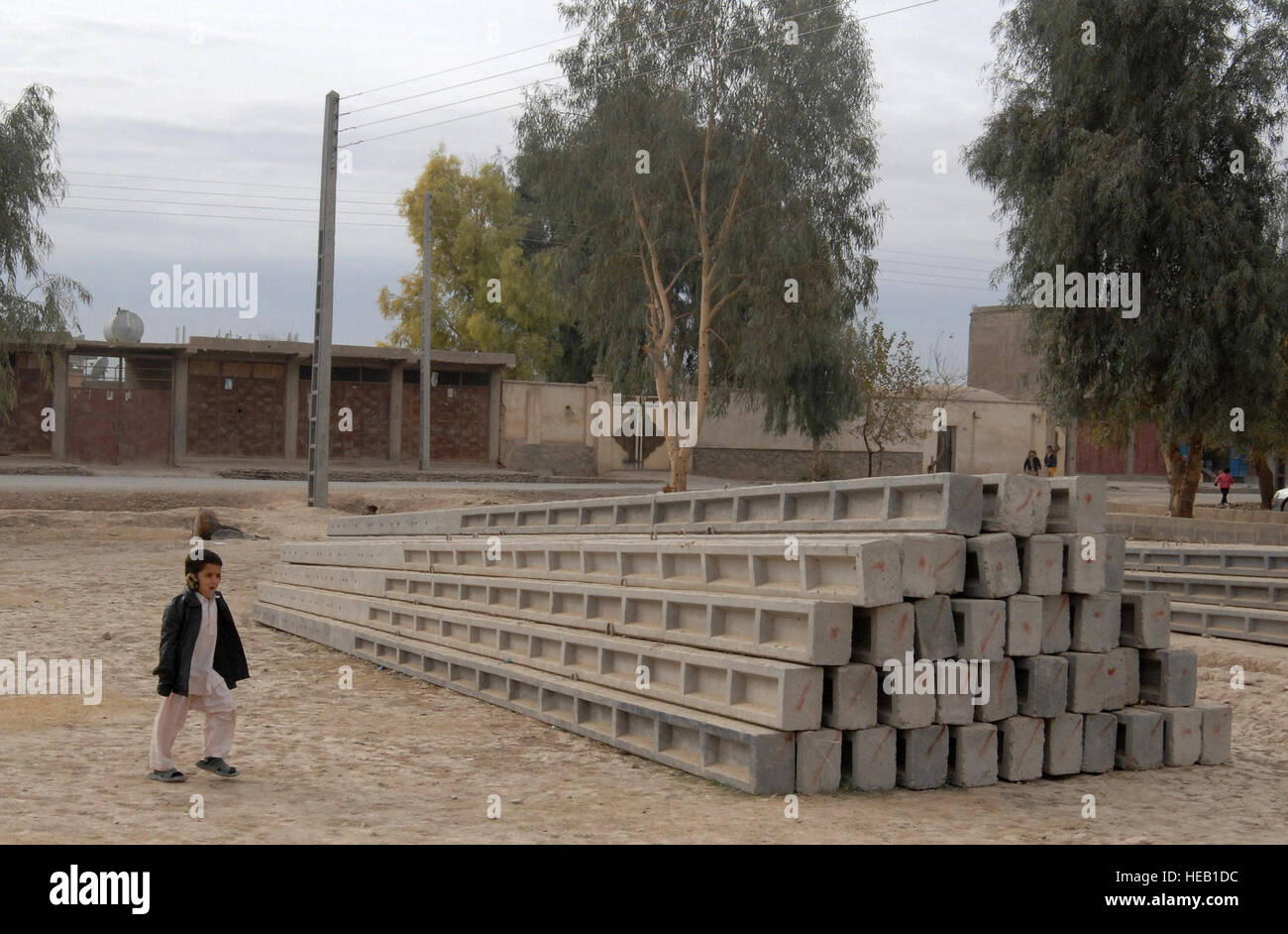 Un piccolo ragazzo afghano passeggiate da alcuni dei pochi rimanenti poli elettrici in attesa di essere installati nel quartiere ho di Farah, Afghanistan, 8 dicembre, 2009. Finora 280 poli sono già stati installati come parte di Farah Provincial Reconstruction Team (PRT) sponsorizzato il progetto di elettrificazione. La potenza elettrica consentirà ai cittadini di Farah per aumentare i loro livelli di igiene, di estendere le ore lavorative, e generalmente aumentano la loro qualità della vita in generale. Foto Stock