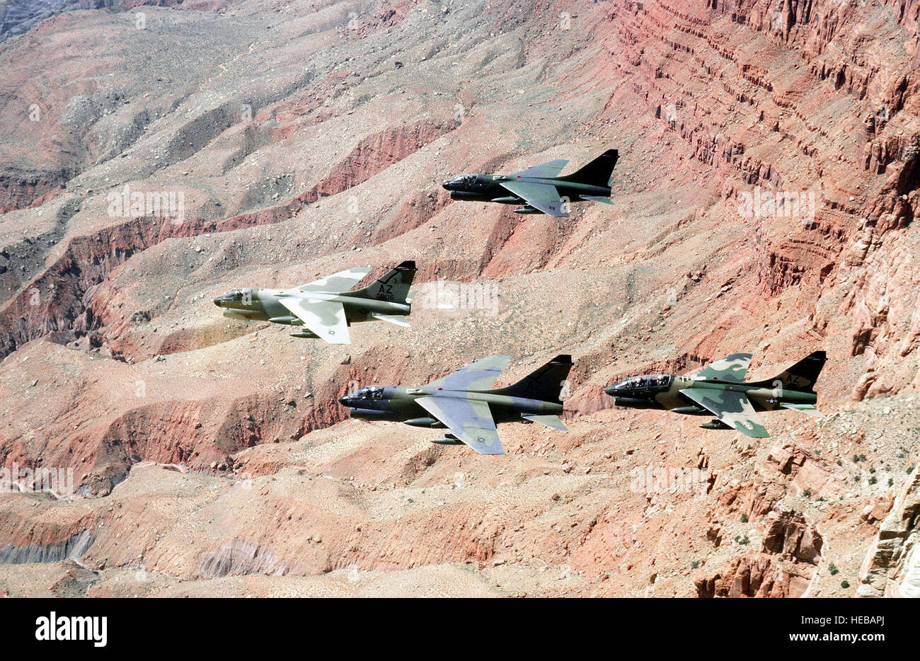 Tre A-7D Corsair II aeromobili e uno A7K Corsair II aeromobili, all'estrema destra, volare in formazione nel deserto. Il velivolo, ciascuna in un diverso schema di verniciatura, vengono testati contro il deserto e la foresta sfondo per la visibilità. Foto Stock
