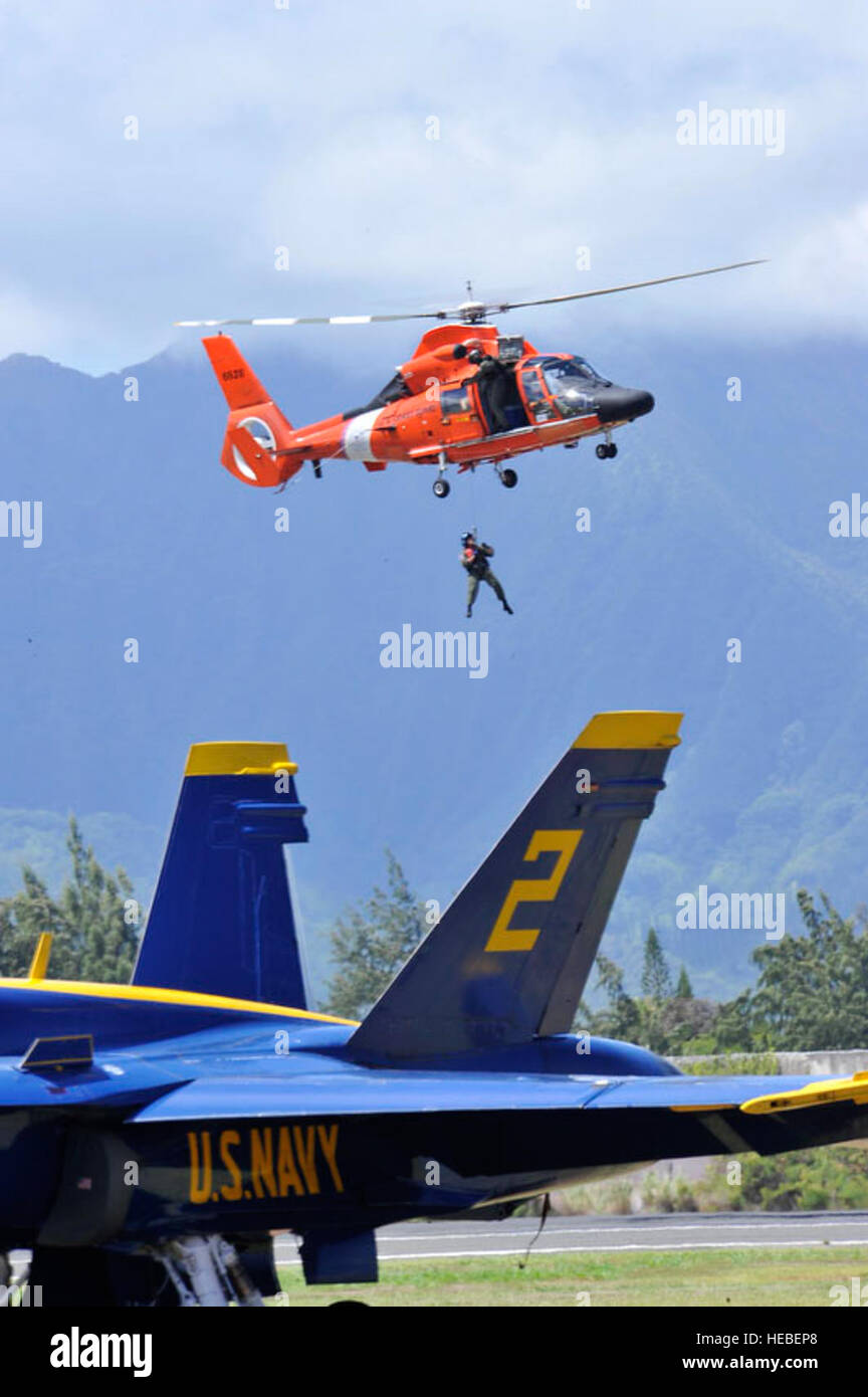 Un U.S. Coast Guard Sailor pende sospesa in aria da un HH-65C/MH-65C Delfino elicottero pur dimostrando l'acqua le operazioni di soccorso durante il 2010 Kaneohe Bay Air Show al Marine Corps base Hawaii in Kailua, Hawaii, Sett. 25, 2010. L'air show, recentemente celebrato ogni tre anni, dispone anche di esibizioni aeree da Red Bull team stunt, un C-17 Globemaster III aeromobili, un F-22 Raptor aeromobile con una antenna team di dimostrazione da Langley Air Force Base, Virginia, e gli Stati Uniti Navy dimostrazione di volo squadrone, Blue Angels. (U.S. Air Force foto di Tech. Sgt. Cohen A. giovani/rilasciato) Foto Stock