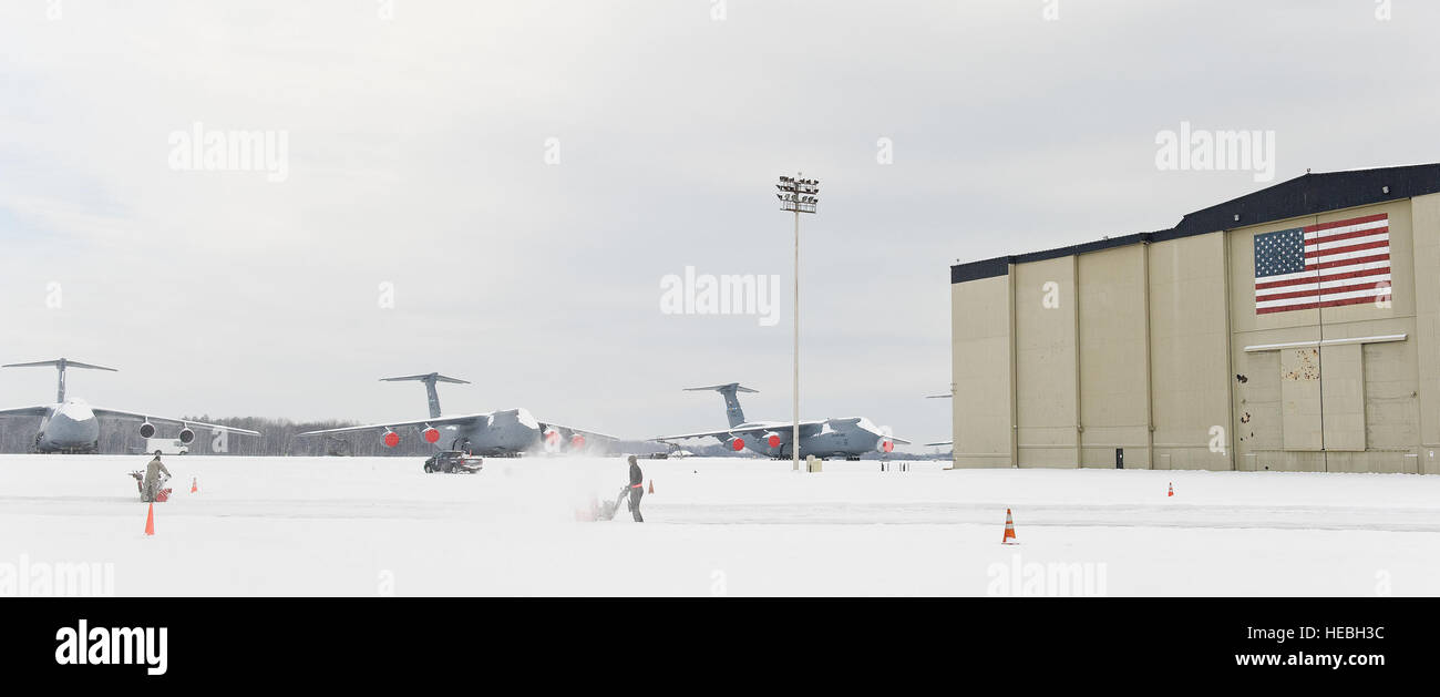 Tre coperte di neve C-5M Super galassie sedersi sulla linea di volo come due team membri di dover cancellare la neve dal lato nord del C-5 isocrone hangar di ispezione di Febbraio 17, 2015, a Dover Air Force Base, Del. personale di base mantenuta la base operativa entro la cancellazione di quattro pollici di neve da marciapiedi, strade e parcheggi, linea di volo, piste di rullaggio e. (U.S. Air Force foto/Roland Balik) Foto Stock