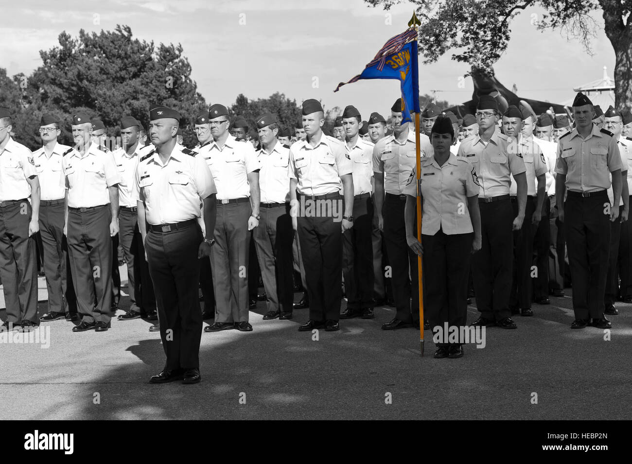 Col. Sarady Tan, 366 Medical Group commander, e una formazione di medici stand all attenzione e preparare per il rendering di un saluto come la bandiera americana viene abbassata ad una cerimonia di ritiro a Montagna Home Air Force Base, Idaho, Sett. 5, 2013. Senior Master Sgt. Sandra Nunes, 366 MDG sovrintendente, trattiene l'unità,contatti guidon, un squadrone standard di dimensioni e le unità più grandi sono autorizzati a trasportare a indicare la loro denominazione gruppo e di appartenenza. (U.S. Air Force illustrazione della foto da Master Sgt. Kevin Wallace/RILASCIATO) Foto Stock