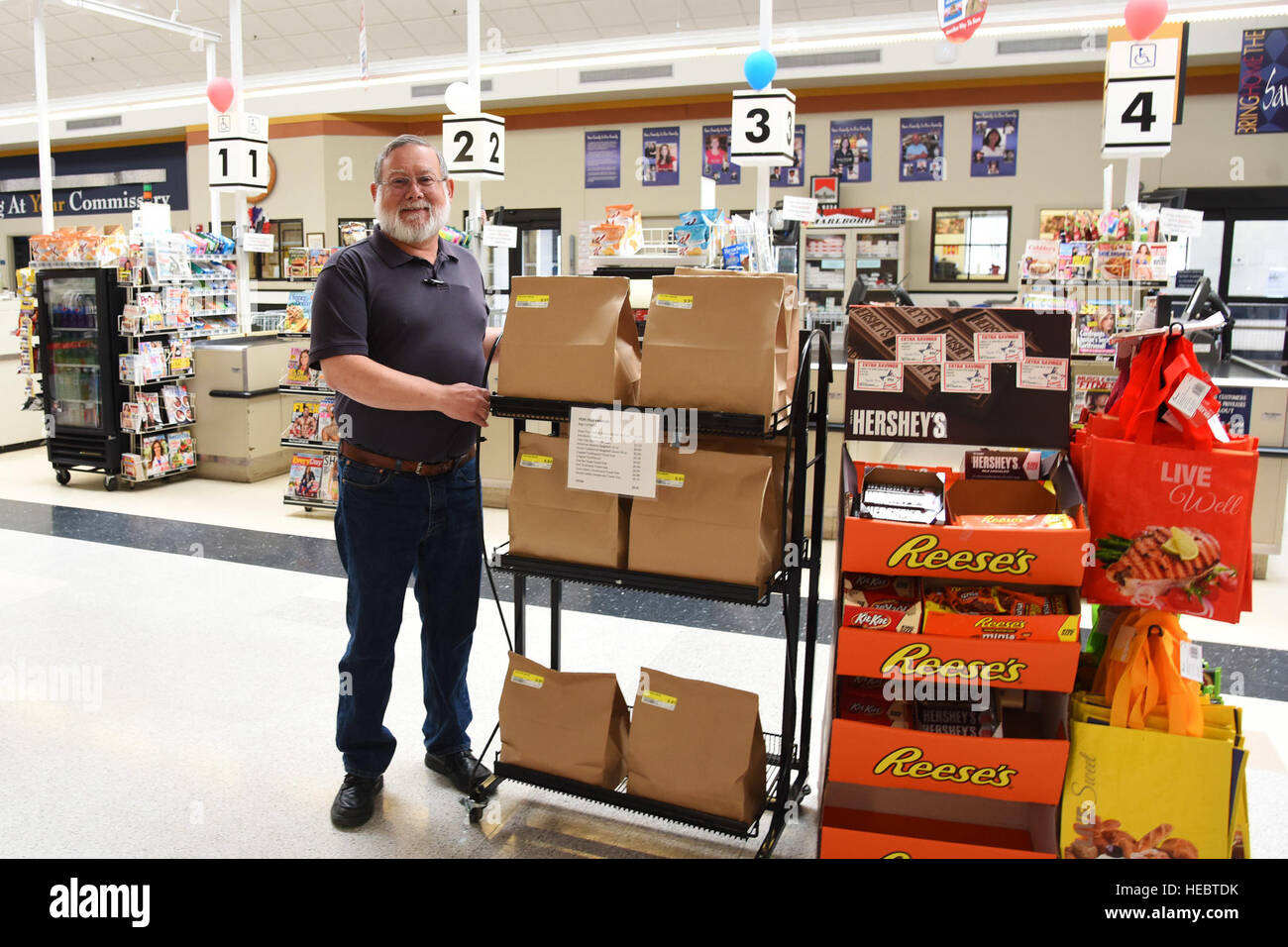 Jerry Contreras, spaccio direttore del negozio, pone accanto a un rack di custom-made sacchetti donazione Giugno 29 sviluppato per la Fed alimenta le famiglie programma a Malmstrom Air Force Base la caserma. Il Comissario serve come base di FFF sede in cui le donazioni sono raccolte e prelevate da cibo locale delle banche. (U.S. Air Force foto di Airman 1. Classe Collin Schmidt) Foto Stock