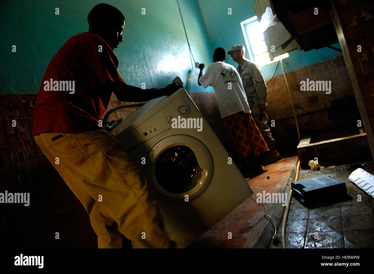 Con l aiuto di un abitante del Gibuti orfano, Builder 1. Classe Mark Gerth prepara l'installazione di una macchina di lavaggio durante una tre-giorni di servizio comune di assistenza comunitaria ai volontari progetto mentre dispiegato per la Combined Joint Task Force - Corno d Africa. Il team di CAV, attraverso donazioni e raccolte di fondi, ha contribuito a rinnovare un ragazzo scuola orfanotrofio chiamato l'Assemblea Mondiale des Jeunes Musulmans Centre National pour la protezione nonché ha donato una macchina lavabiancheria. Foto Stock