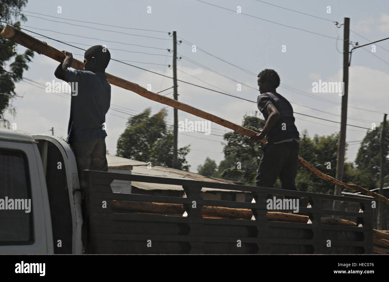 Due ragazzi di sollevare un registro che saranno utilizzati nella costruzione dal letto di un carrello parcheggiato lungo la strada di Negele Borena, Etiopia, Dicembre 4, 2011. (U.S. Air Force foto di Senior Airman Jarad Denton/rilasciato) Foto Stock