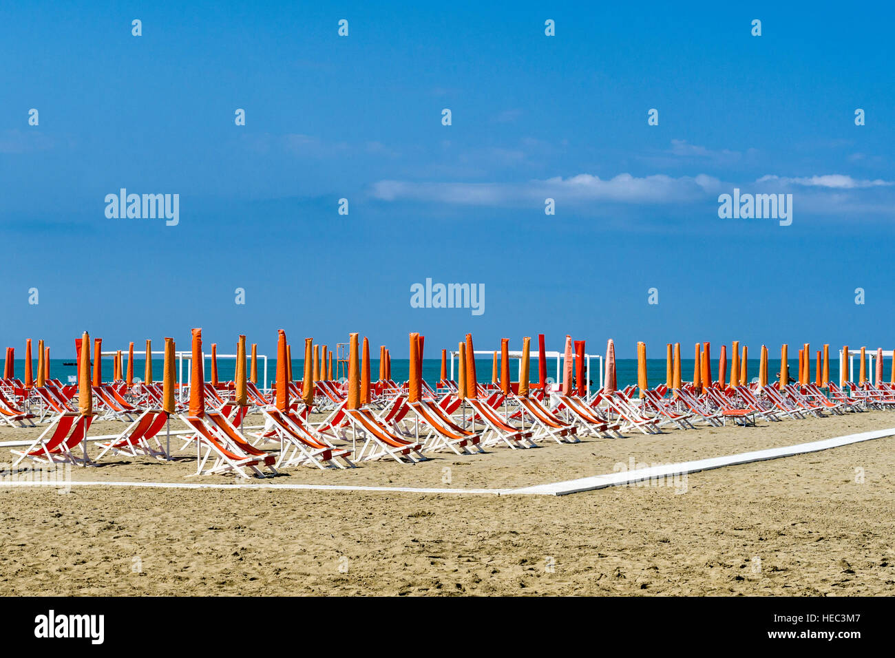 Arancione vuota di ombrelloni e sdraio in spiaggia Foto Stock