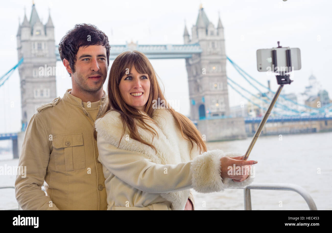 Attraente coppia giovane prendendo un selfie nella parte anteriore del Ponte della Torre di Londra. Foto Stock