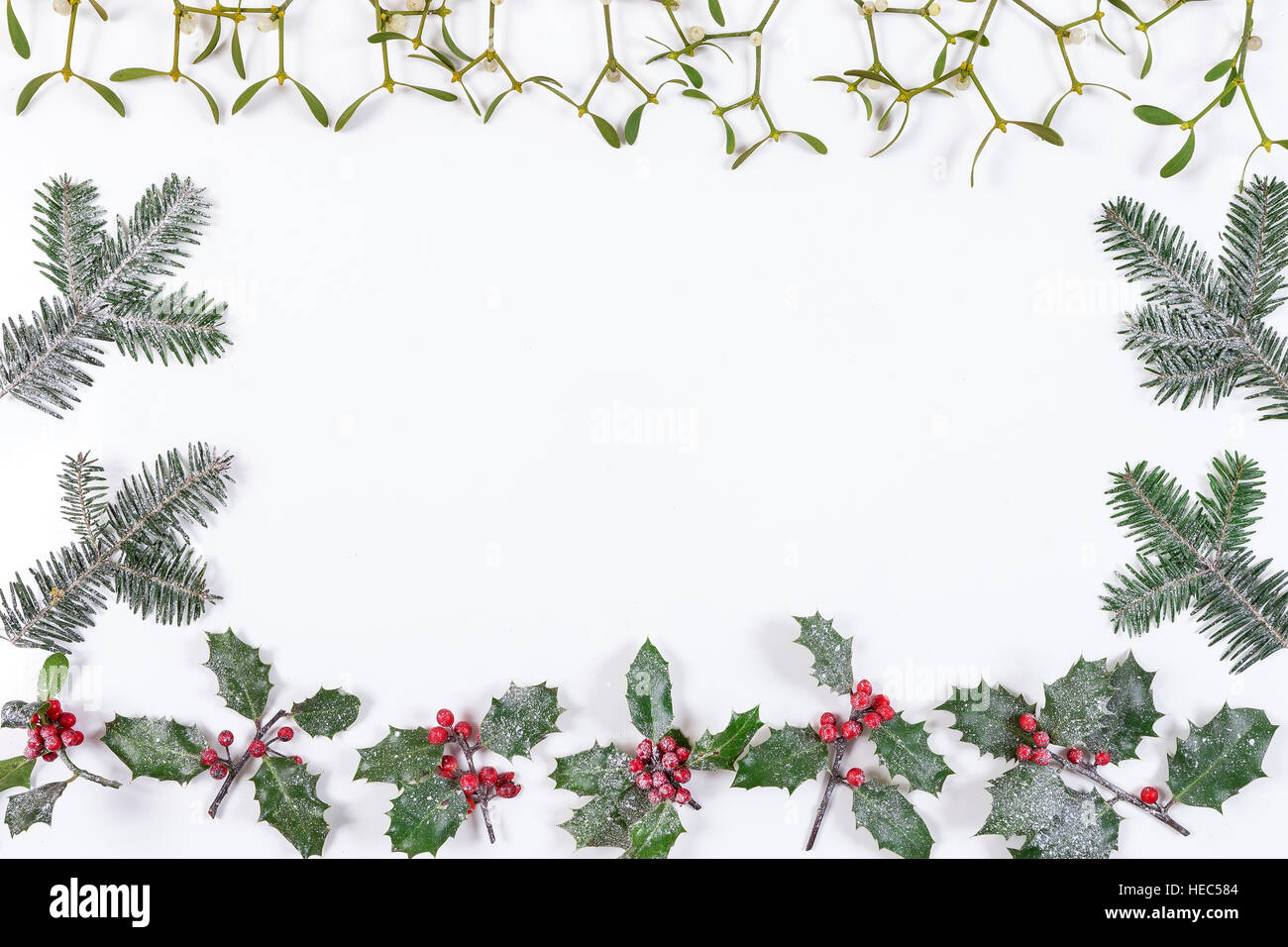 Natale sfondo decorativo con decorazioni, agrifoglio, vischio e coperta di neve di cedro bianco cypress Foto Stock