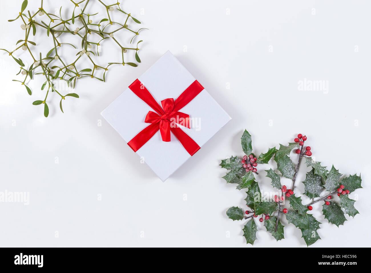 Natale sfondo decorativo angolo con nastro rosso dono e decorazioni, agrifoglio, vischio bianco aon Foto Stock