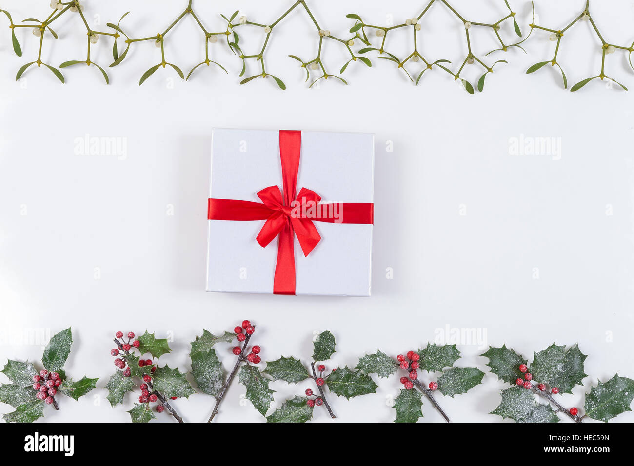 Natale sfondo decorativo angolo con nastro rosso dono e decorazioni, agrifoglio, vischio bianco aon Foto Stock