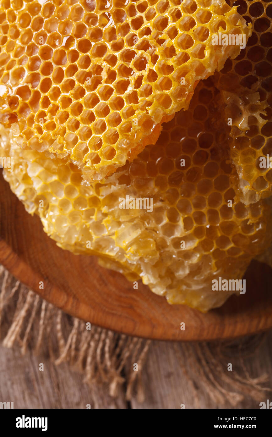 Favo di miele nel piatto di legno sul tavolo macro. verticale vista superiore Foto Stock