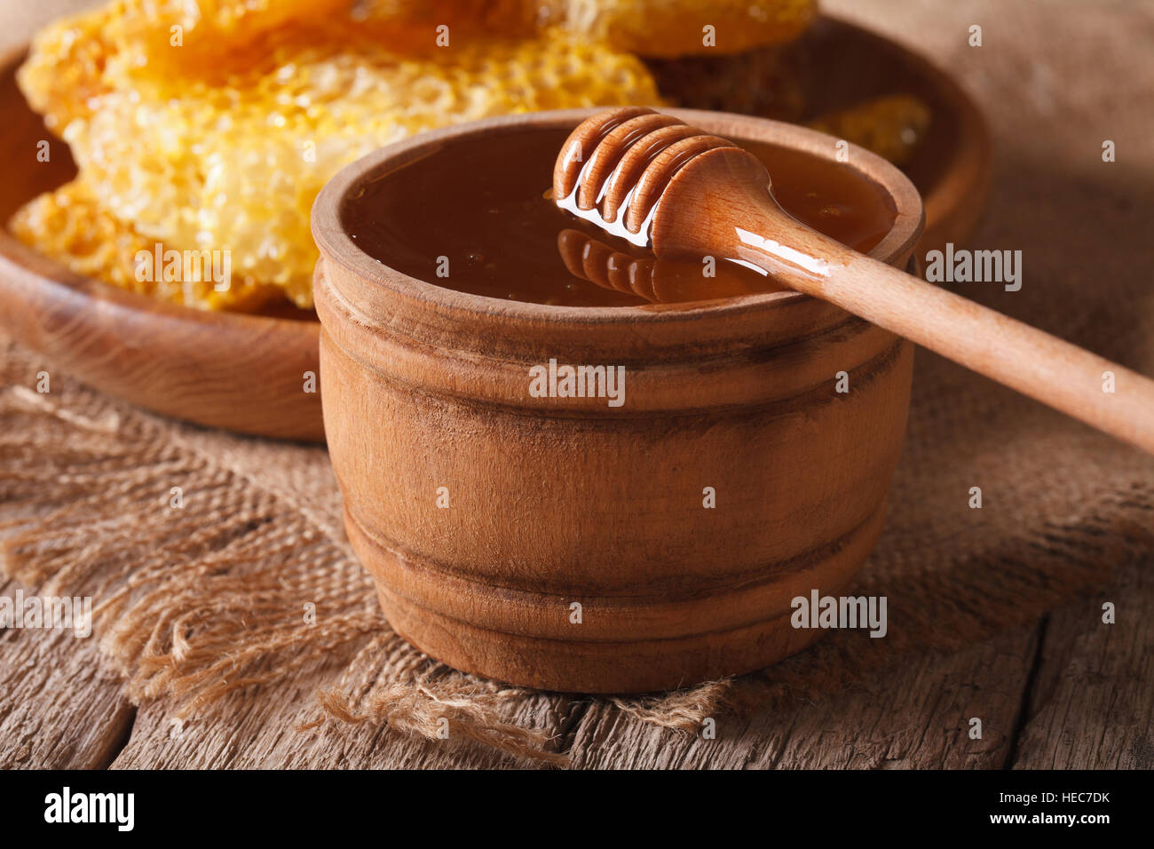 Miele di fresco in una ciotola di legno e nido vicino sul tavolo orizzontale. Foto Stock