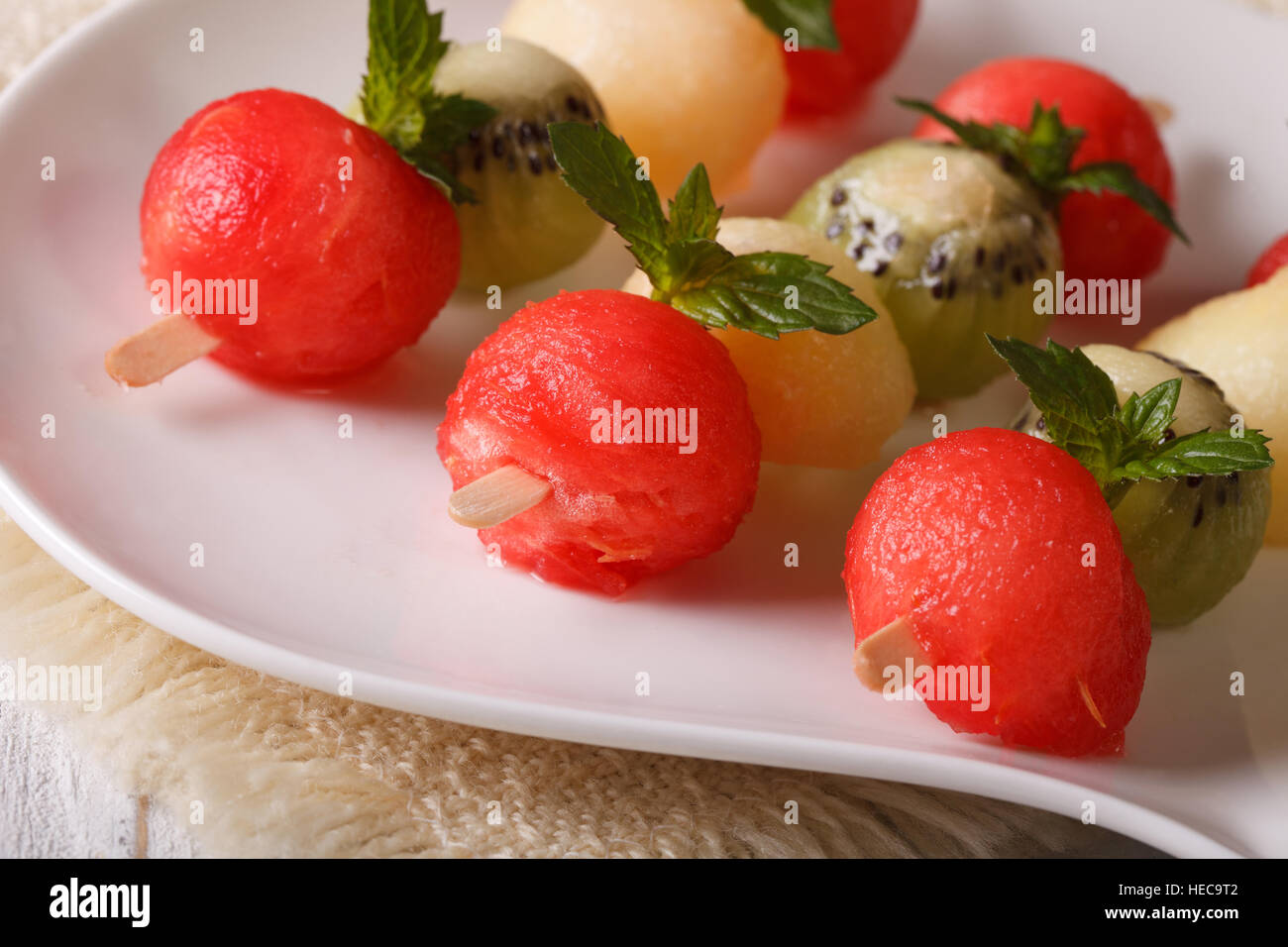 Palline di cocomero, kiwi e melone su spiedini di close-up su una piastra orizzontale. Foto Stock