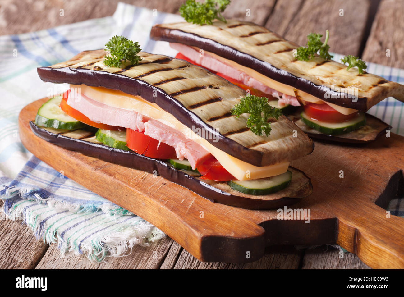 Sandwich di melanzane con verdure fresche, prosciutto e formaggio vicino sul tavolo orizzontale. Foto Stock
