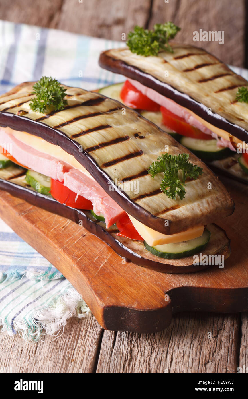 Delizioso e sano sandwich di melanzane con verdure fresche, prosciutto e formaggio vicino. In verticale Foto Stock